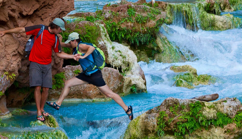 Couple helping each other cross a river